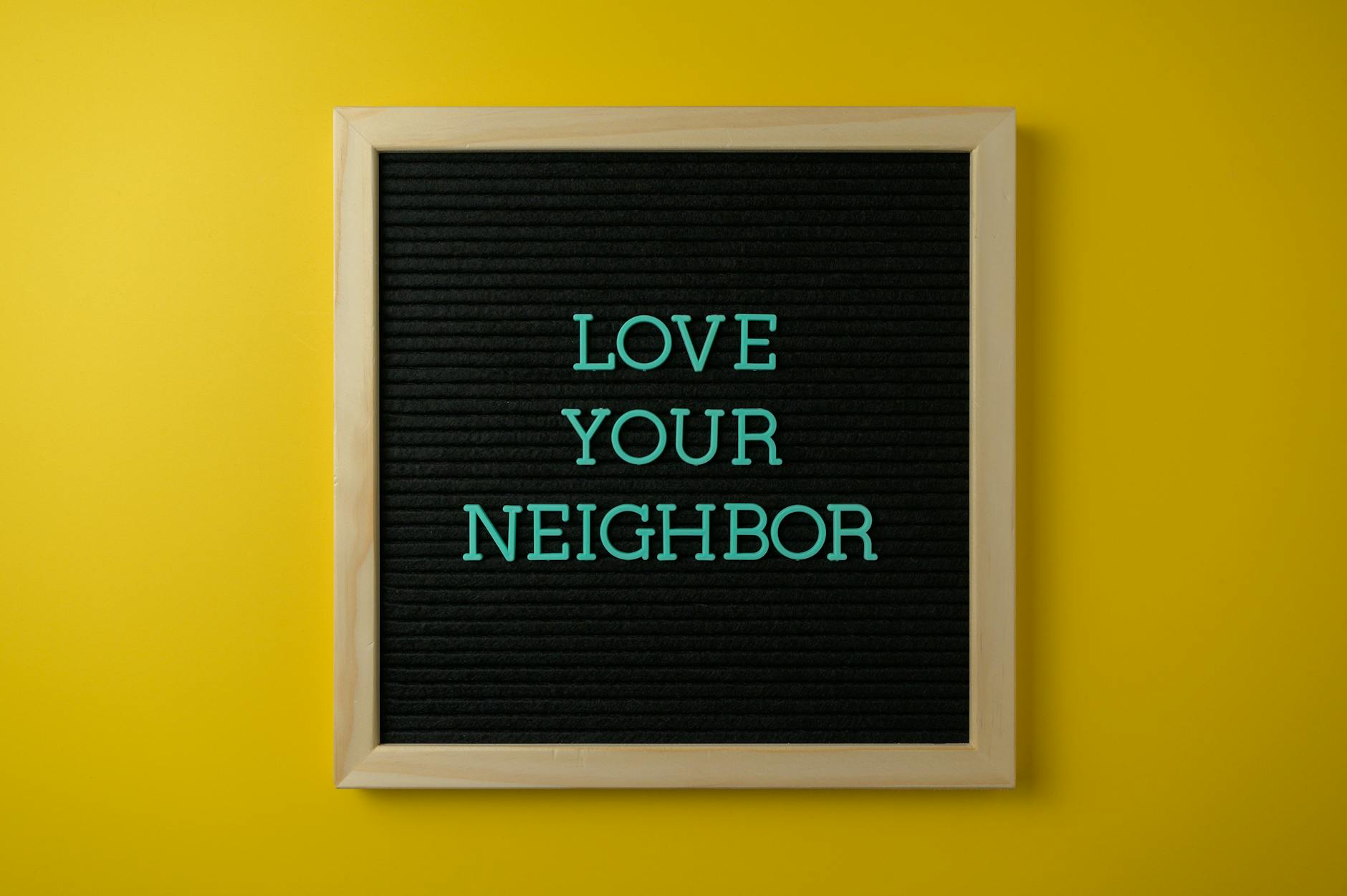 framed board with a slogan on a yellow wall